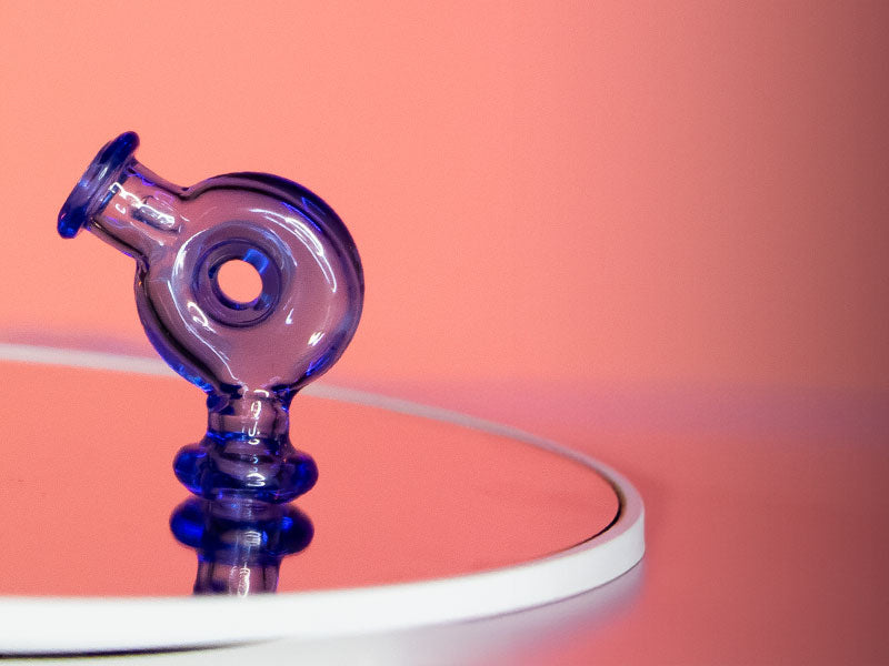 Wulf Ring Pivot Top on reflective glass surface with pink studio background